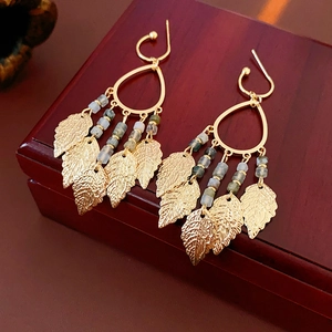 Détail de boucles d'oreilles à franges feuille avec monture dorée et perles colorées