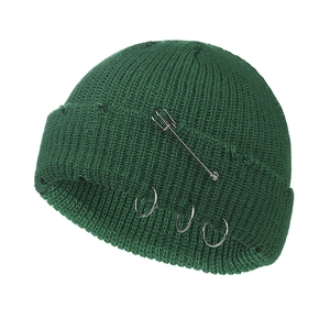 Detailed knit texture of dark green beanie with silver pin and metal rings design