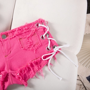 Dettaglio degli shorts in denim rosa con occhielli metallici e lacci laterali