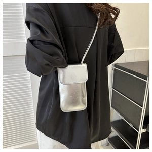 Silver glossy square crossbody bag shown with a black outfit and minimalist background