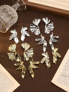 Flat lay of vintage gold and silver oversized floral leaf earrings on retro paper