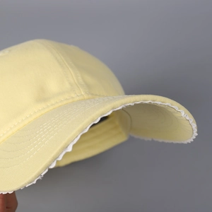 Détail d'une casquette en coton jaune clair avec bordure en dentelle blanche délicate