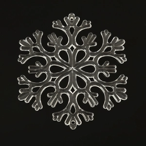 Macro shot of transparent acrylic snowflake decoration with hanging hole on black background