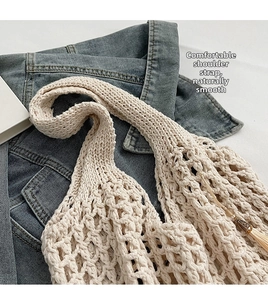 Detail of hand-woven cream tote bag showing mesh crochet texture and tassel charm