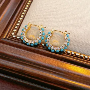 18k gold plated hoop earrings with turquoise beads and clear zircon on a wood frame