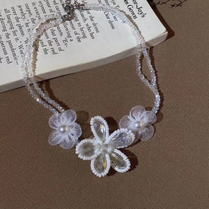 Macro view of crystal flower necklace with pearl details and woven beaded chain
