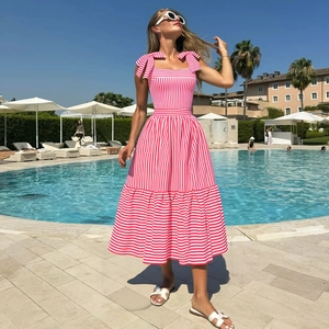 Women's red and white striped one-piece swimsuit with bow shoulder straps poolside