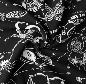 Detail of black zodiac tapestry showing white astrological patterns and fine fabric texture