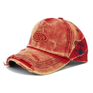 Detail view of red distressed baseball cap with Boston embroidery and torn brim edge