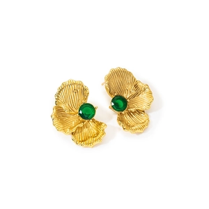 Detail showing vintage gold flower earrings with emerald green stone and textured petals