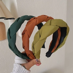 Detail of hand-woven braided headbands in forest green, rust red and olive green fabric