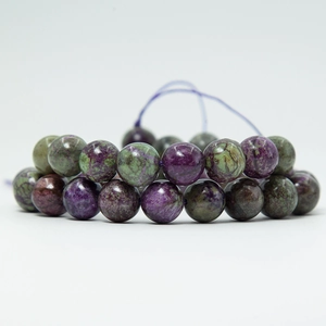 Macro view of purple and green Stichtite round gemstone beads on white background