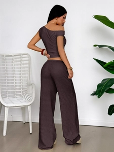 Rear view of woman wearing elegant dark textured one-shoulder top and wide-leg trousers set