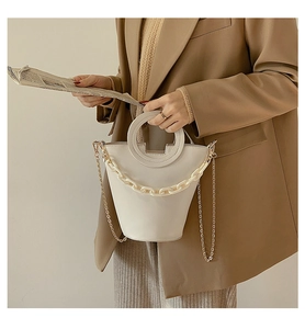Detail of cream bucket bag with round cutout handle and stylish thick chain strap