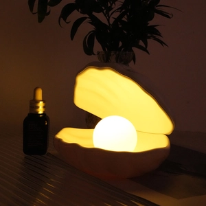 Detail of warm pearl light inside a ceramic shell lamp on a cozy bedside table