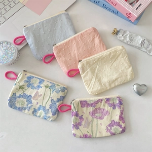 Flat lay of small floral and textured fabric coin purses with magenta lanyards on a desk