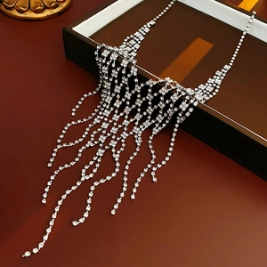 Macro detail of silver V-shaped fringe necklace with sparkling crystals on dark surface