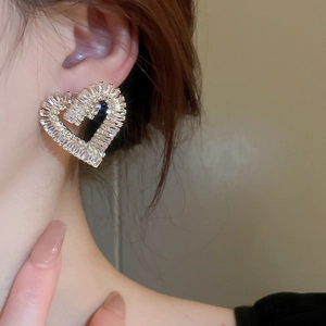 Gros plan de boucles d'oreilles cœur en zircon plaqué or portées par un modèle