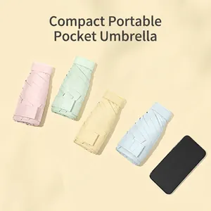 Flat mini pocket umbrellas in pastel colors next to a phone showing compact size