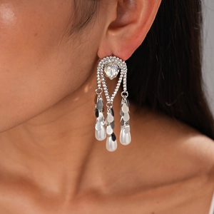 Détail de boucles d'oreilles plaquées or 18k avec perles d'imitation et pompons de cristaux
