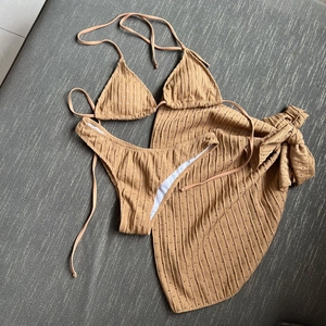 Detailed flat lay of three-piece camel bikini with rib texture and subtle polka dots