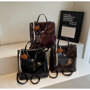 Three vintage faux leather backpacks in black, burgundy and brown with teddy bear charms