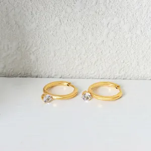 Minimalist gold hoop earrings with sparkling round zircon charms on a clean white surface