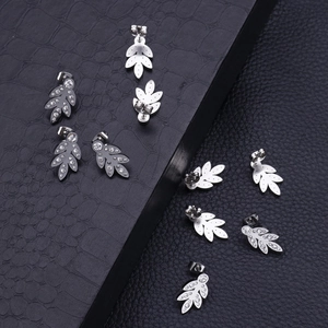 Detailed view of eight silver leaf-shaped stud earrings with crystals on black leather