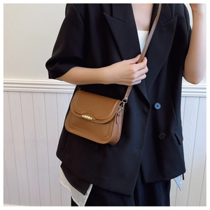 Détail d'un petit sac bandoulière marron vintage avec un fermoir rotatif en métal doré