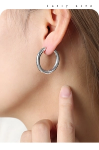 Macro view of polished silver hoop earring on model showing smooth metallic texture