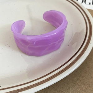 Macro shot of purple acrylic open bangle with translucent wavy ripple texture details