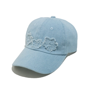 Light blue denim baseball cap with three distressed floral patches on a white background
