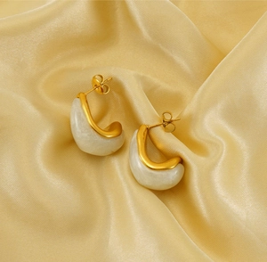 Detail of vintage gold plated teardrop earrings on elegant yellow silk fabric