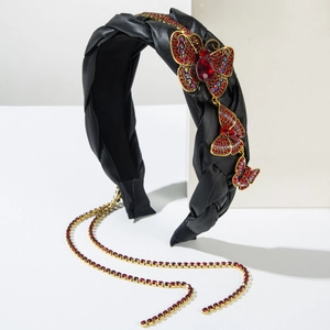 Detail eines schwarzen Lederstirnbands mit goldenen Strass-Schmetterlingen und Quaselkette