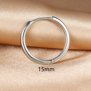 Macro detail of a 15mm silver huggie hoop earring on champagne satin fabric background
