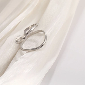 Detail of irregular geometric silver titanium steel ring with polished finish on white fabric