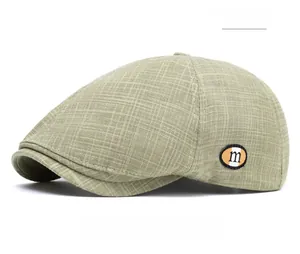 Detail der khakifarbenen Karo-Baskenmütze mit 'm'-Patch und atmungsaktivem Leinenstoff
