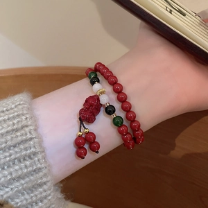 Gros plan d'un bracelet en perles rouges avec un pendentif Pi Xiu traditionnel au poignet