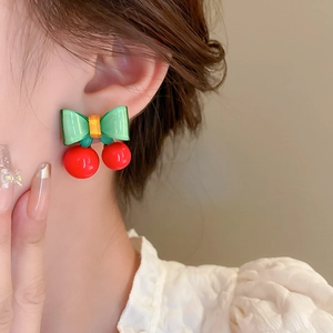 Gros plan détaillé de boucles d'oreilles cerise portées par un mannequin dans un ton doux
