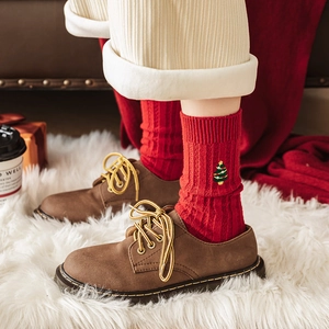 Chaussettes de Noël rouges avec broderie sapin et bottines en cuir sur tapis moelleux