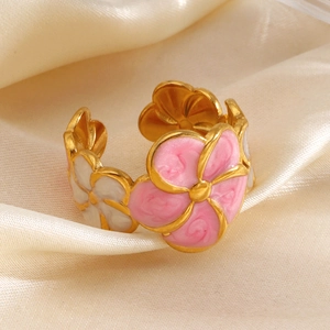 Golden flower ring with pink and white enamel petals on a beige silk fabric