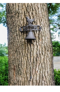 Detail of rustic cast iron welcome bell with bird statue and textured dark finish