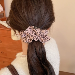 Detail of pink leopard print hair scrunchie worn on head with small black decorative tag