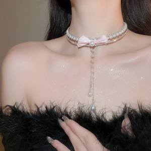 Detail of elegant choker with pink bow, double-layer pearl chain, and long tassel drop