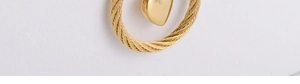 Detailed close-up of golden cable-textured earrings with a smooth heart-shaped pendant