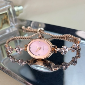 Detail of rose gold oval watch featuring pink rhinestones and leaf-shaped metal strap