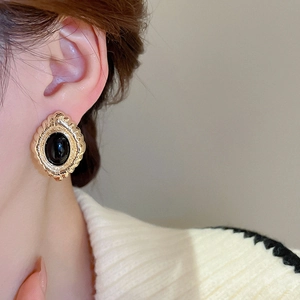 Detail of vintage oval gold earring with black center stone on a model's ear