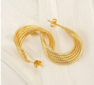 Macro detail of 18k gold plated multi-layer C-shape earrings with twisted braided texture