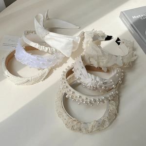 Detailed composition of white pearl and lace headbands with bow accents in soft lighting