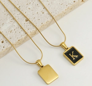 Detail of 18k gold-plated letter K pendant with black inlay on a sleek snake chain